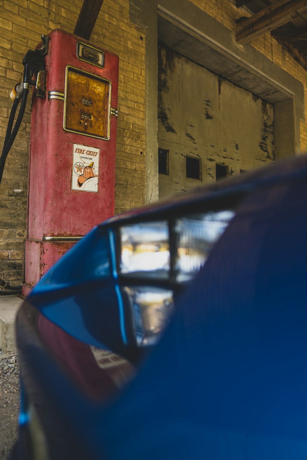 um carro azul estacionado ao lado de uma cabine telefônica vermelha