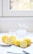 A bright kitchen scene with a bowl of fresh lemons and a jar of fermented lemons.