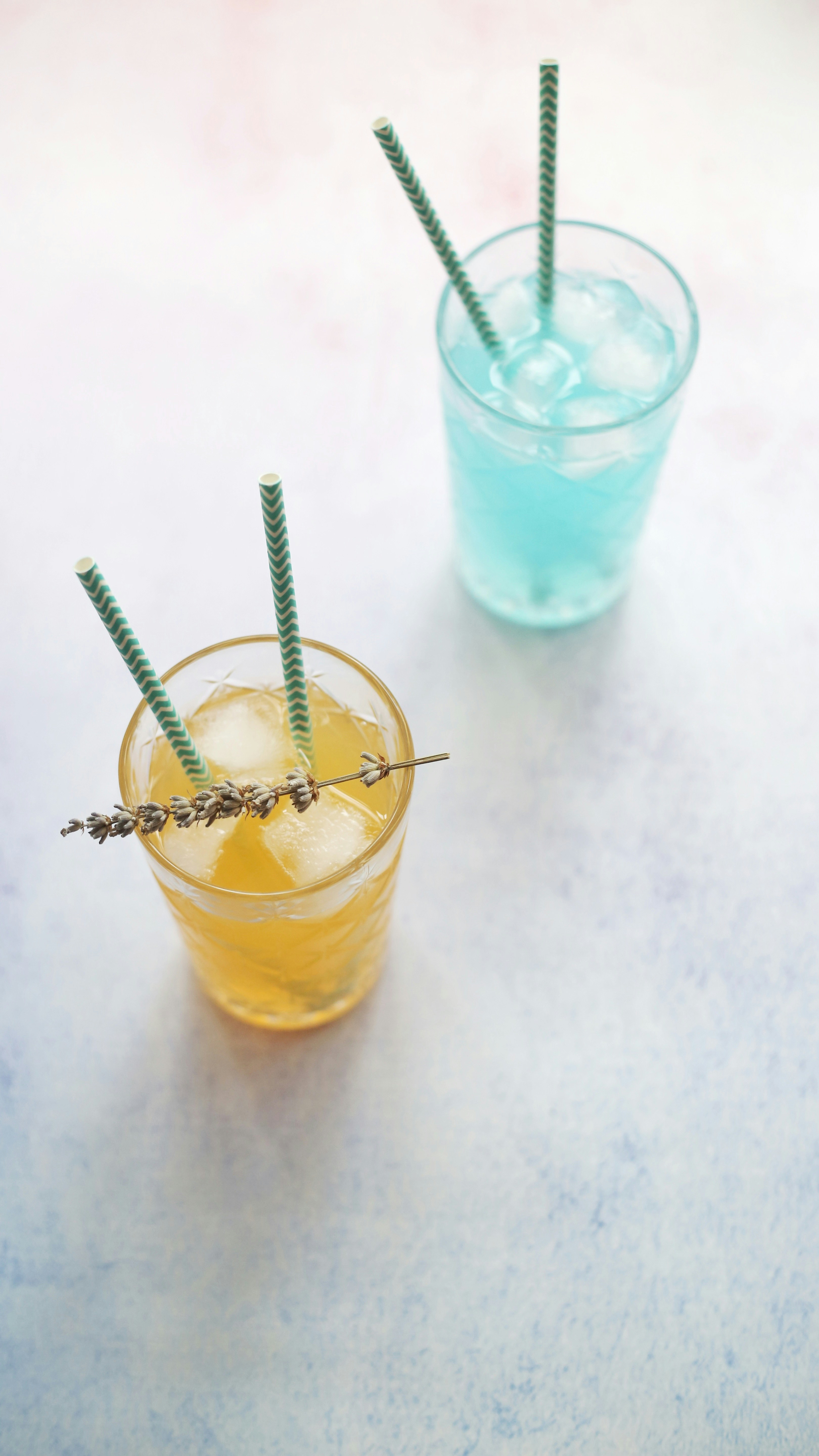 Colorful cold beverages in cups with ice and straws on bright yellow background