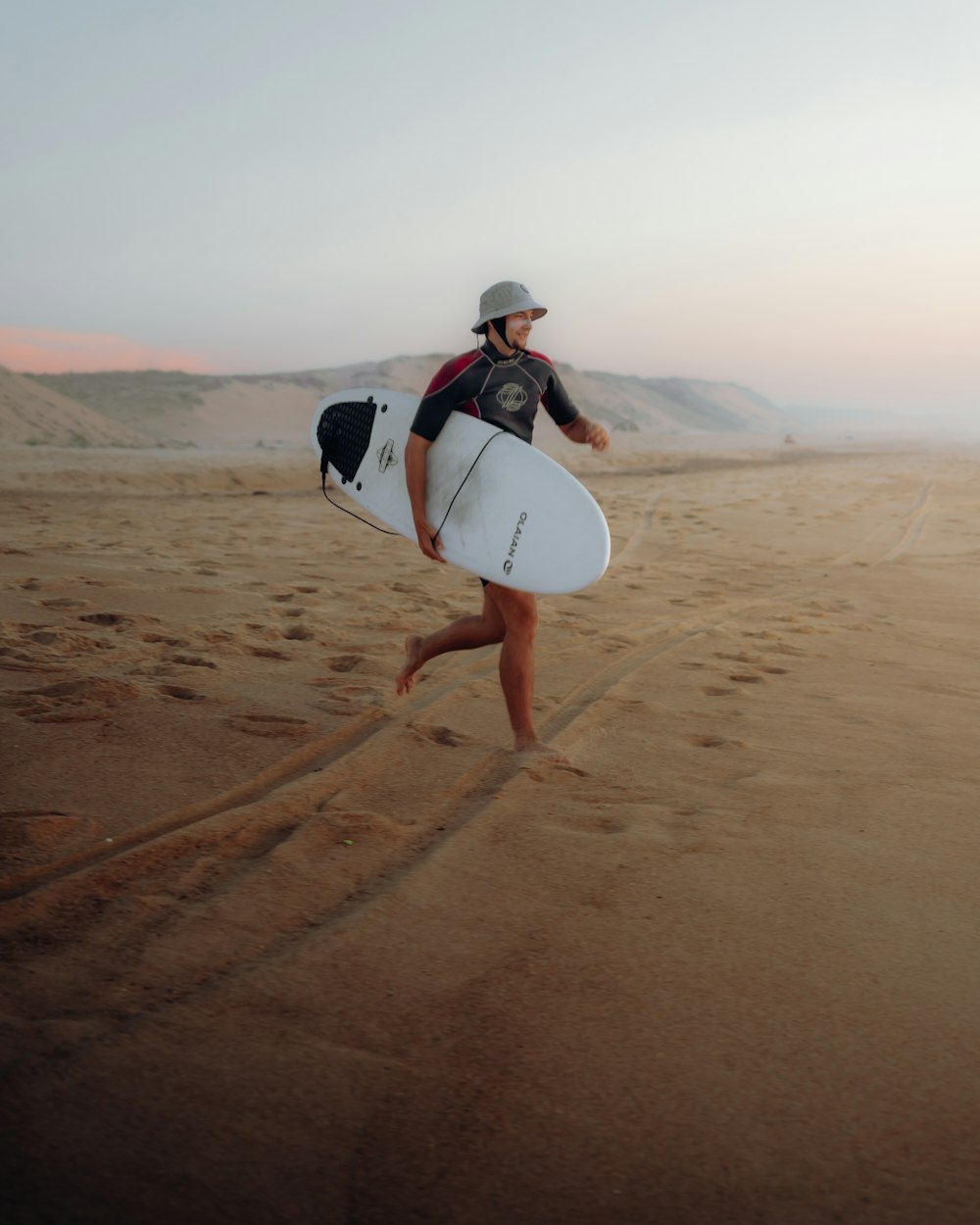 a person carrying a surfboard on a sandy beach