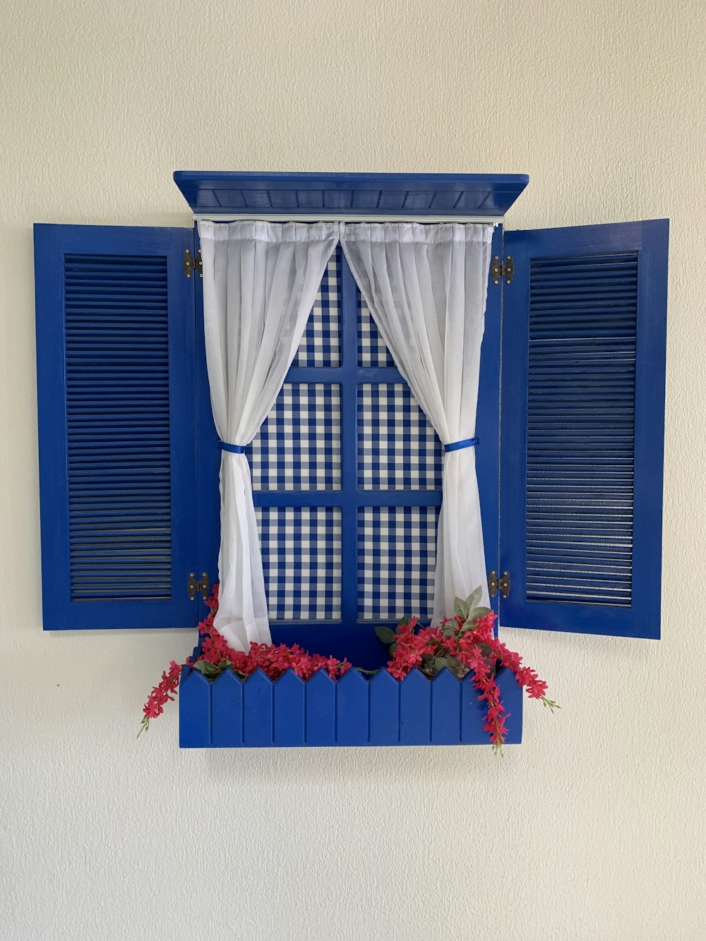 a window with blue shutters and flowers in front of it