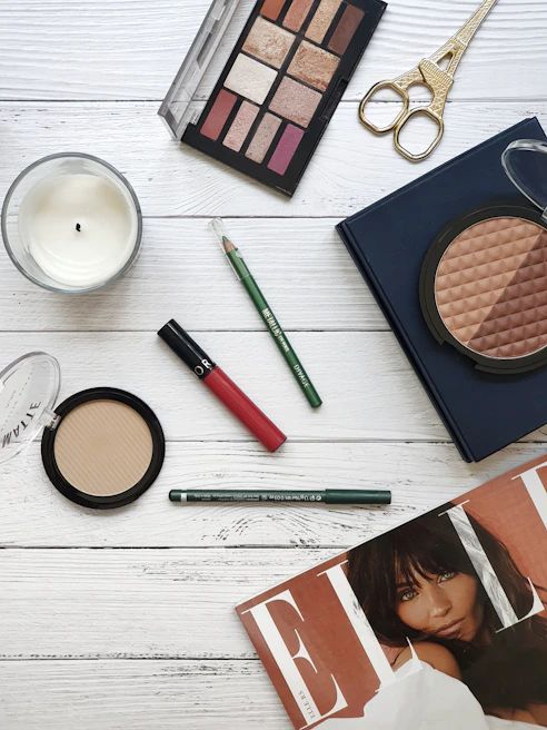 Flat lay of vibrant makeup products including lipsticks and eyeshadows on a marble surface