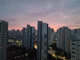 High-rise apartment building with city skyline at dusk.
