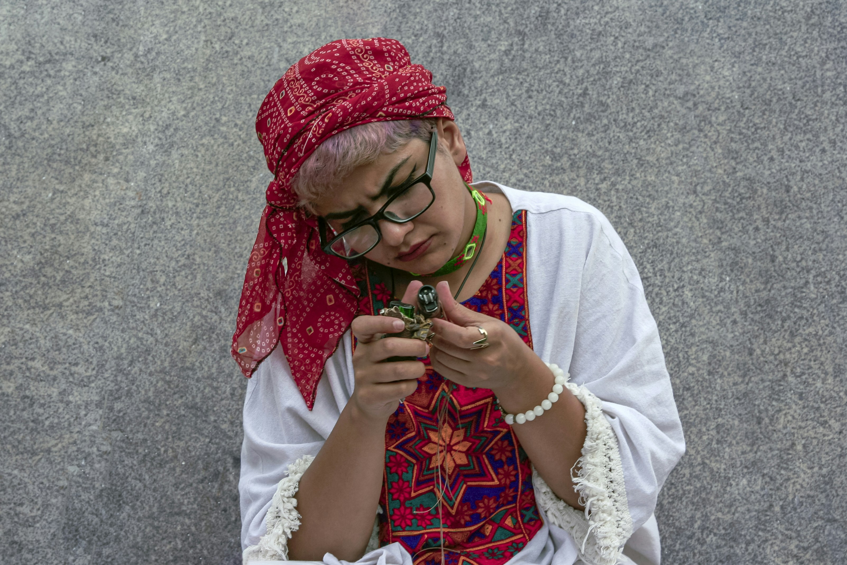 a person wearing a red hat and glasses holding a small green object