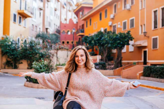 A smiling woman holding her phone with a vibrant Brazilian street scene in the background.