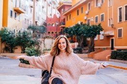 A smiling woman holding a map, standing in a charming Prague alleyway adorned with colorful buildings.