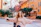 A cheerful woman using her phone outdoors with colorful Brazilian architecture behind her.
