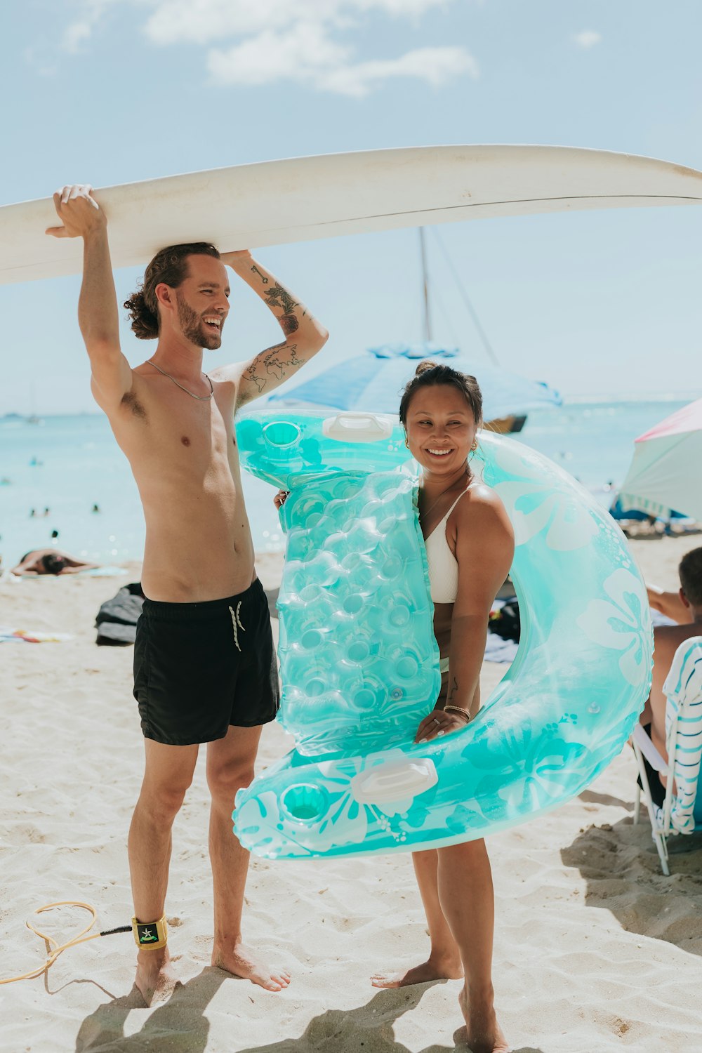 a man and woman holding a surfboard on a beach