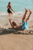 a man lying on his back in the water with a woman in the background