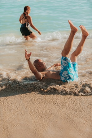 a man lying on his back in the water with a woman in the background