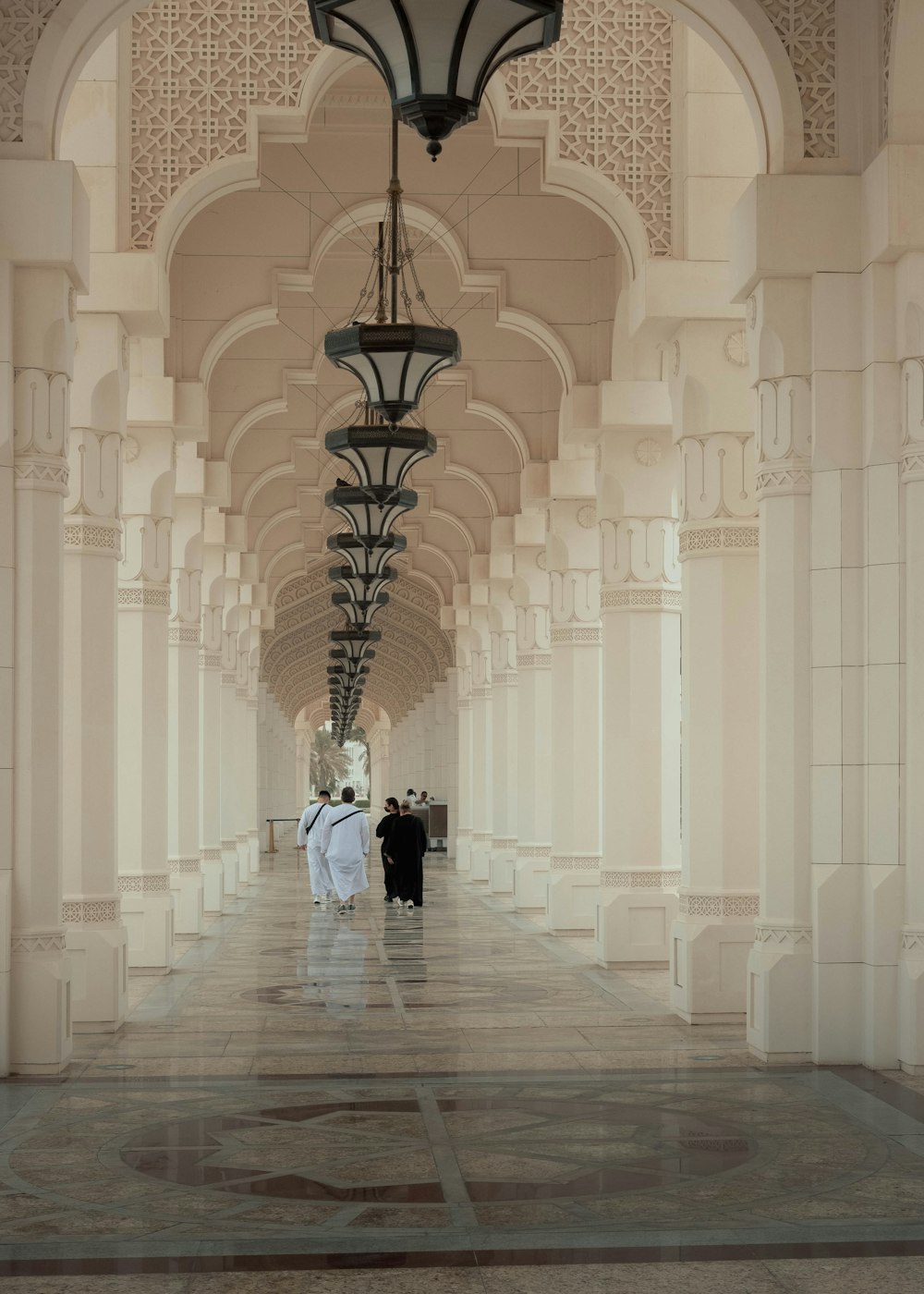 a couple of people walking in a large building with a large chandelier