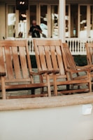 Large patio rocking chair set made of weathered wood on a sunny porch.