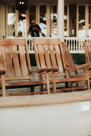 Large patio rocking chair set made of weathered wood on a sunny porch.