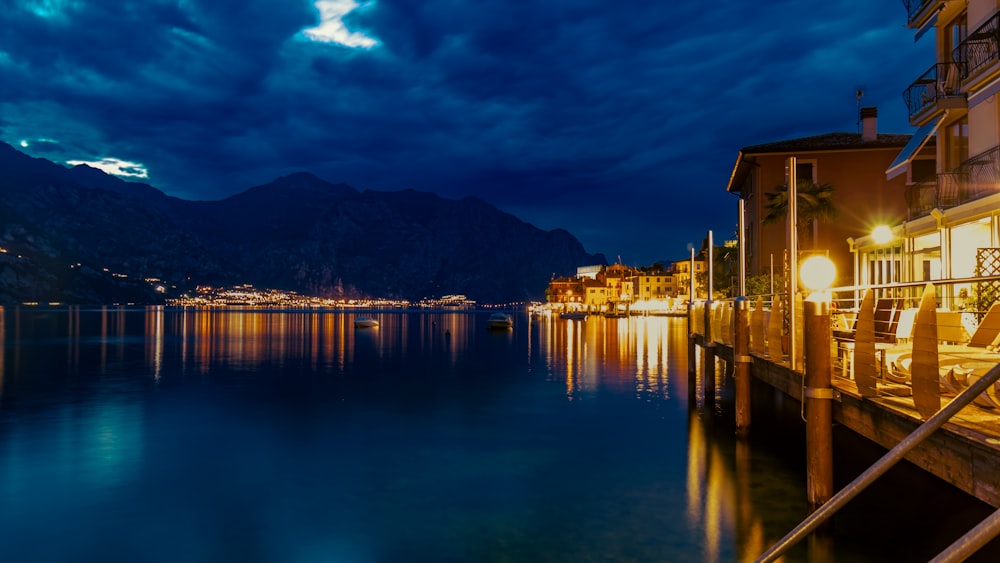 a body of water with buildings and mountains in the background