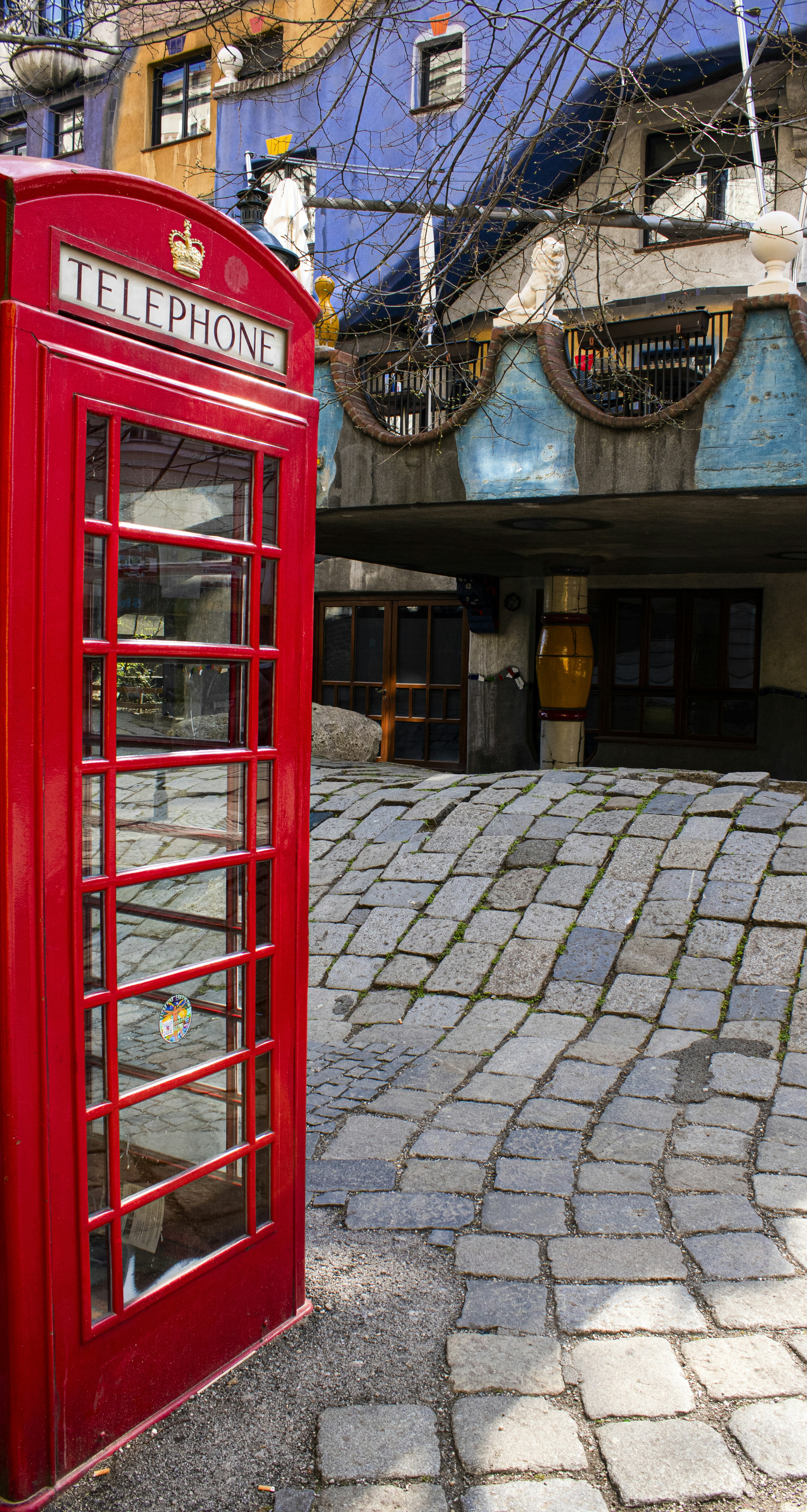 a red telephone booth on a brick street