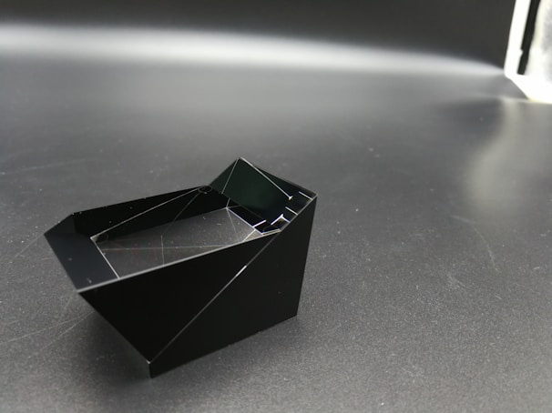 Minimalist dichavador made of matte black metal, resting on a cracked ice surface.