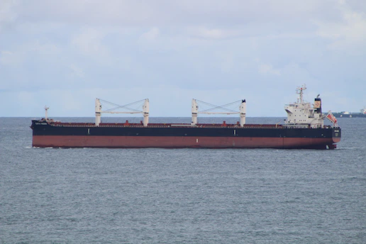 A modern black and silver cargo ship sailing on calm blue waters