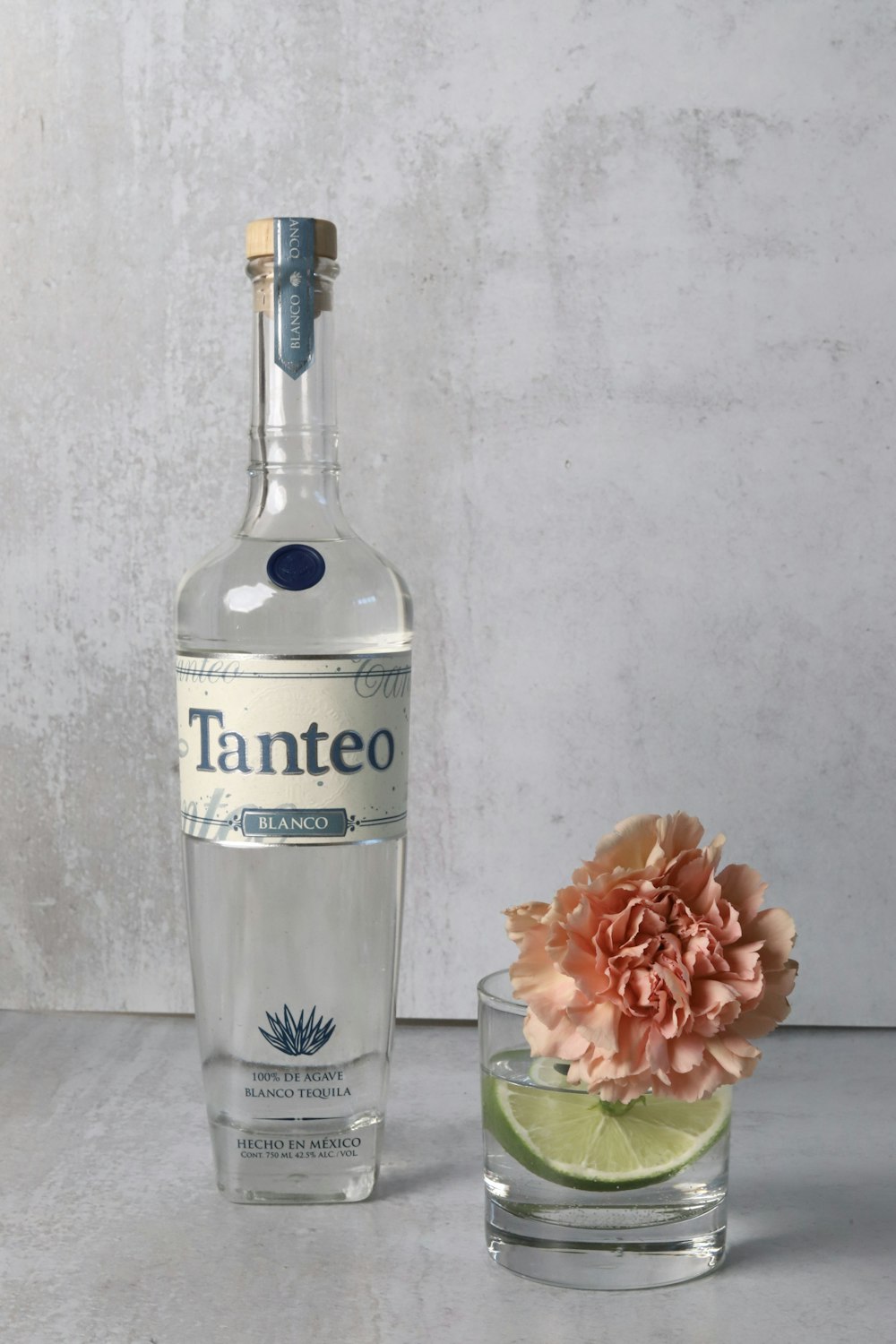 a bottle of water next to a flower in a glass