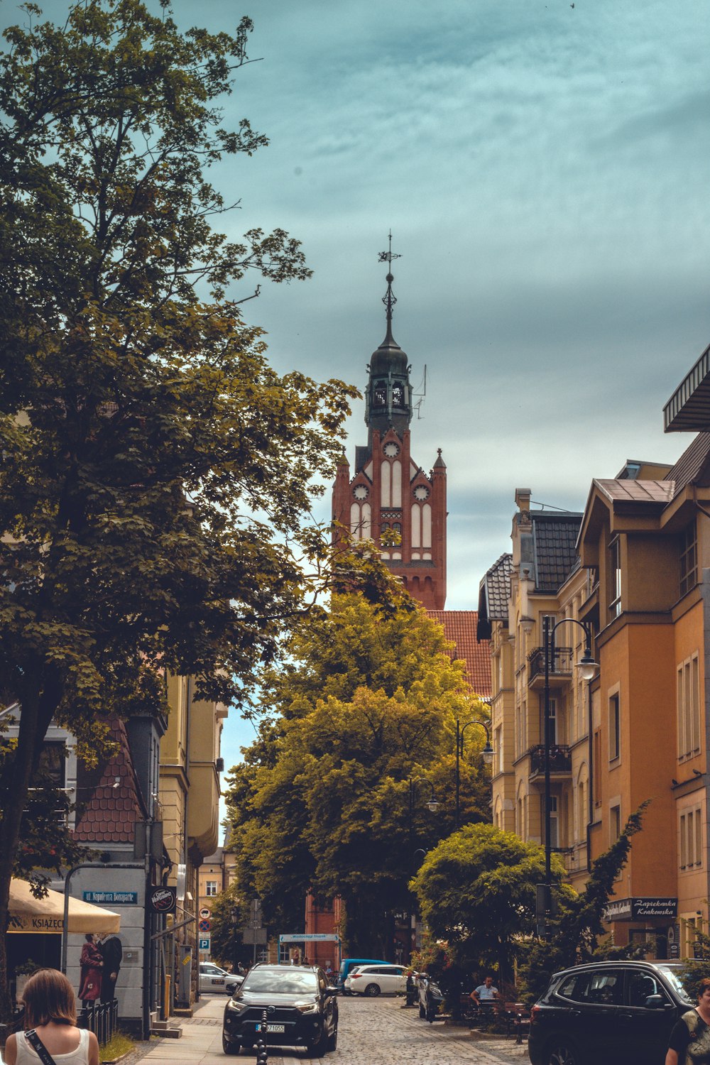 a street with cars and trees on the side and buildings on the side