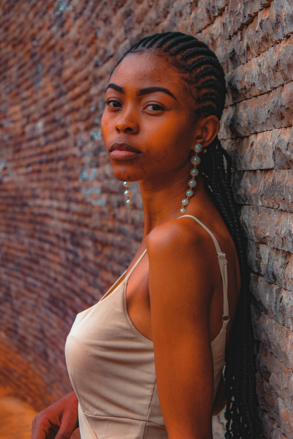 a woman leaning against a brick wall