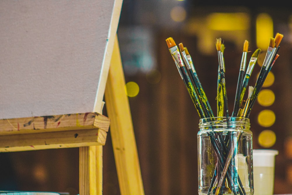 a group of brushes sit in a glass cup