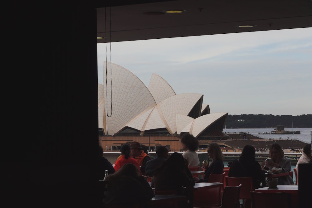 a group of people sitting at a table looking out at a large building