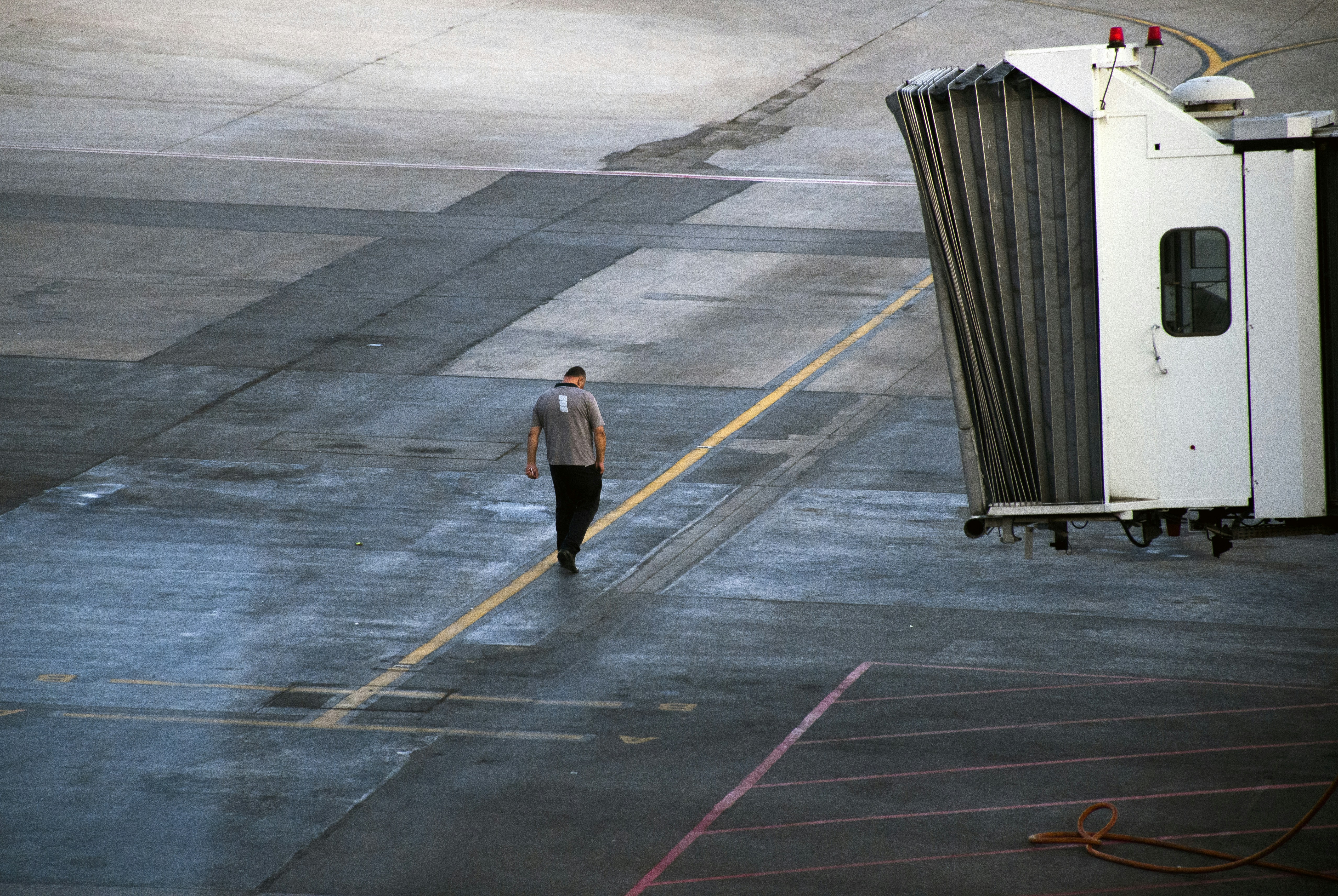a person walking on a wet road, A worker at the airport.