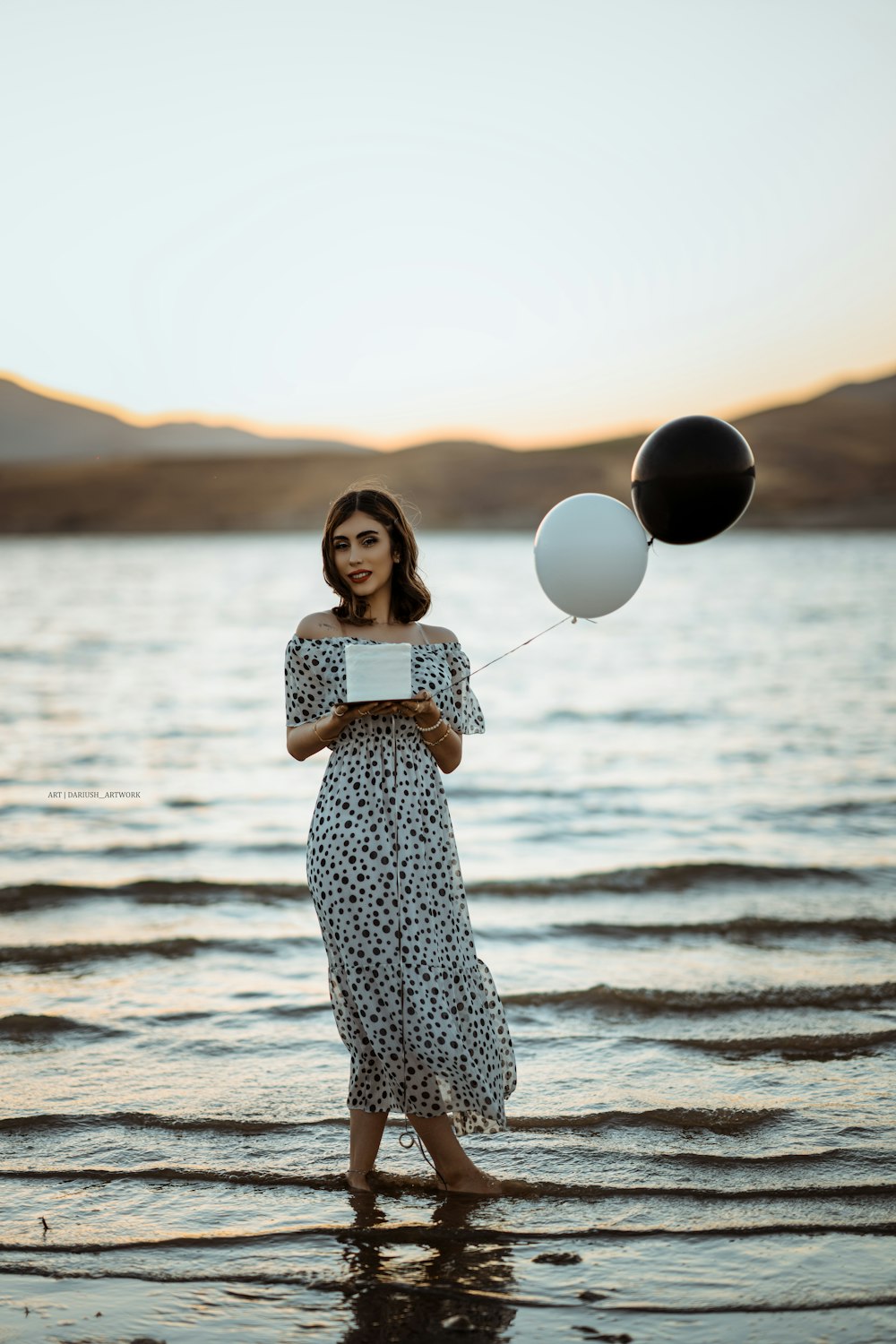 a person holding balloons on a beach