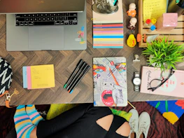 A vibrant flat lay of social media icons, a notebook, and colorful pens on a clean white desk.