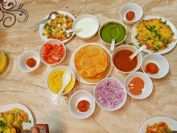 A vibrant spread of Indian breakfast dishes including golden poha and stuffed parathas on a rustic wooden table.