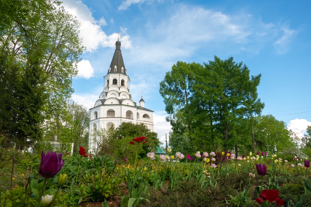 a garden with flowers and a church in the background