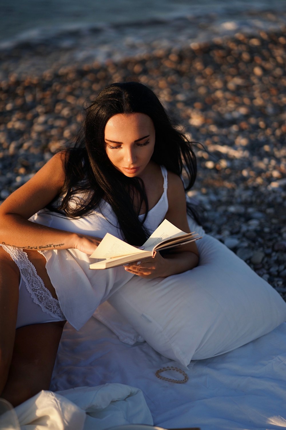 a woman lying on a beach reading a book