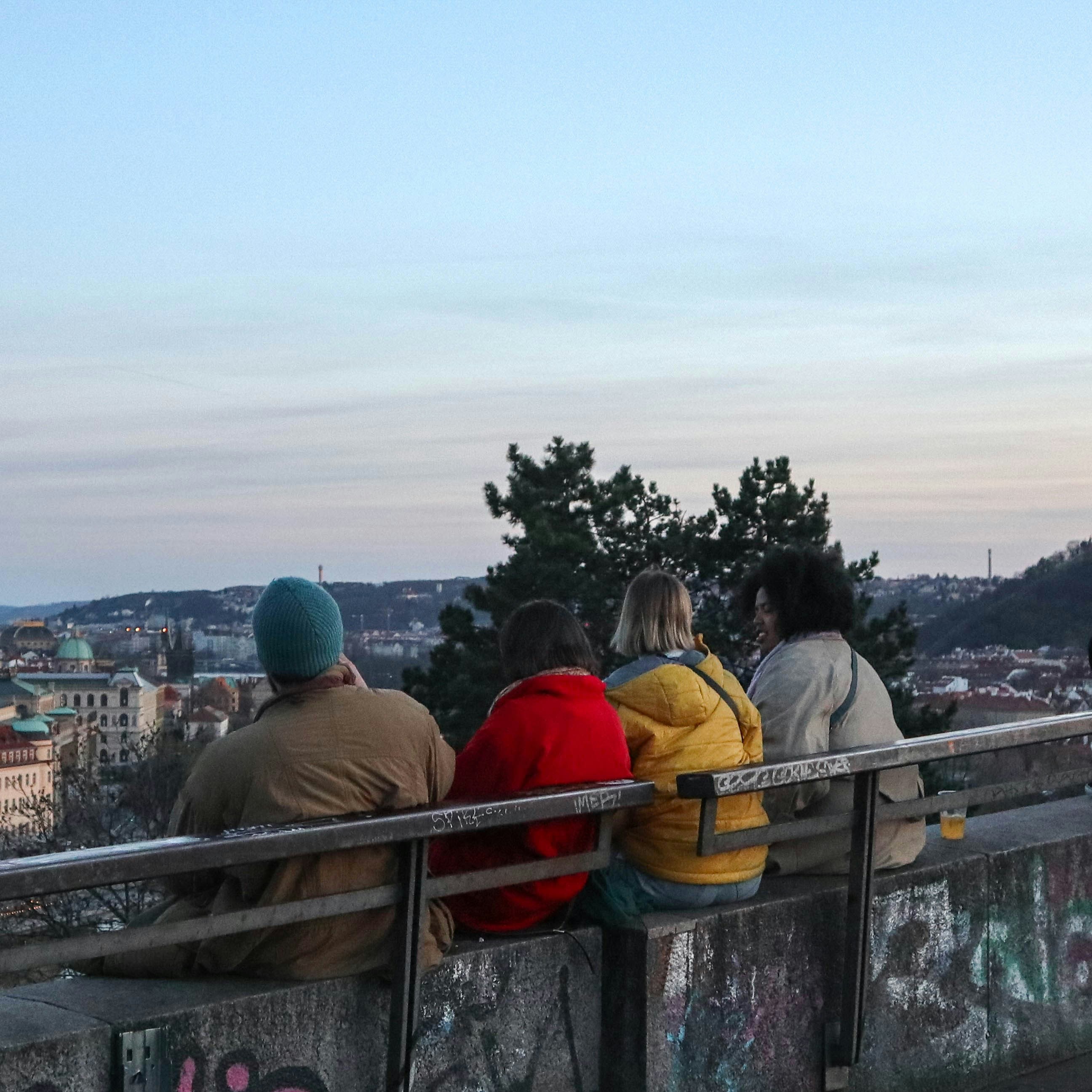 A group of people sitting on a railing overlooking a city photo – Free ...