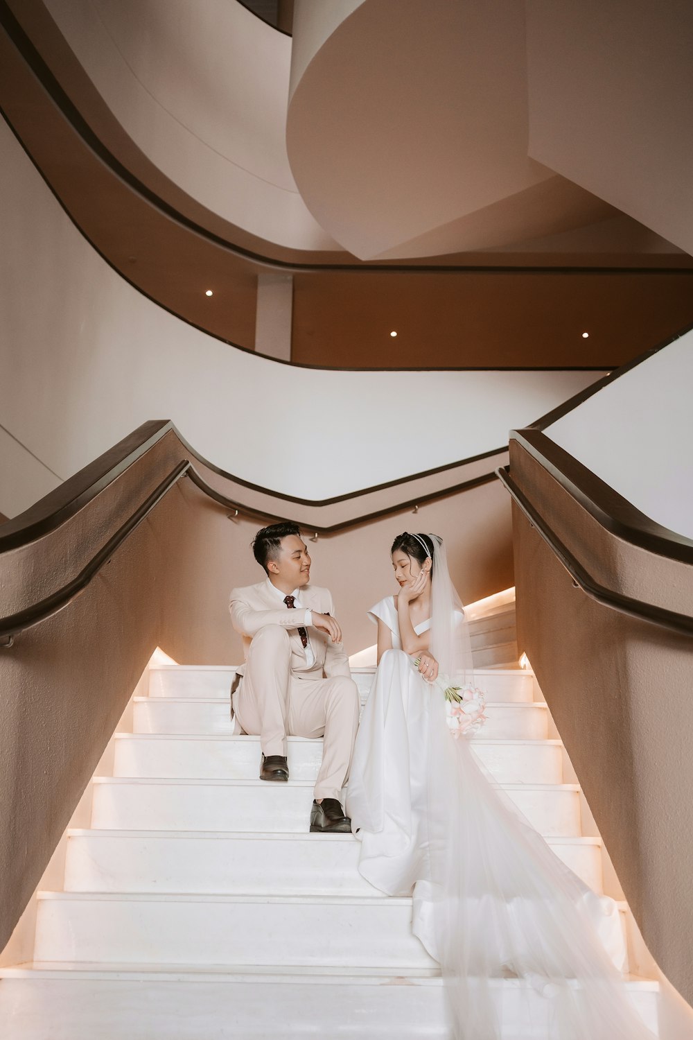 a bride and groom sitting on stairs