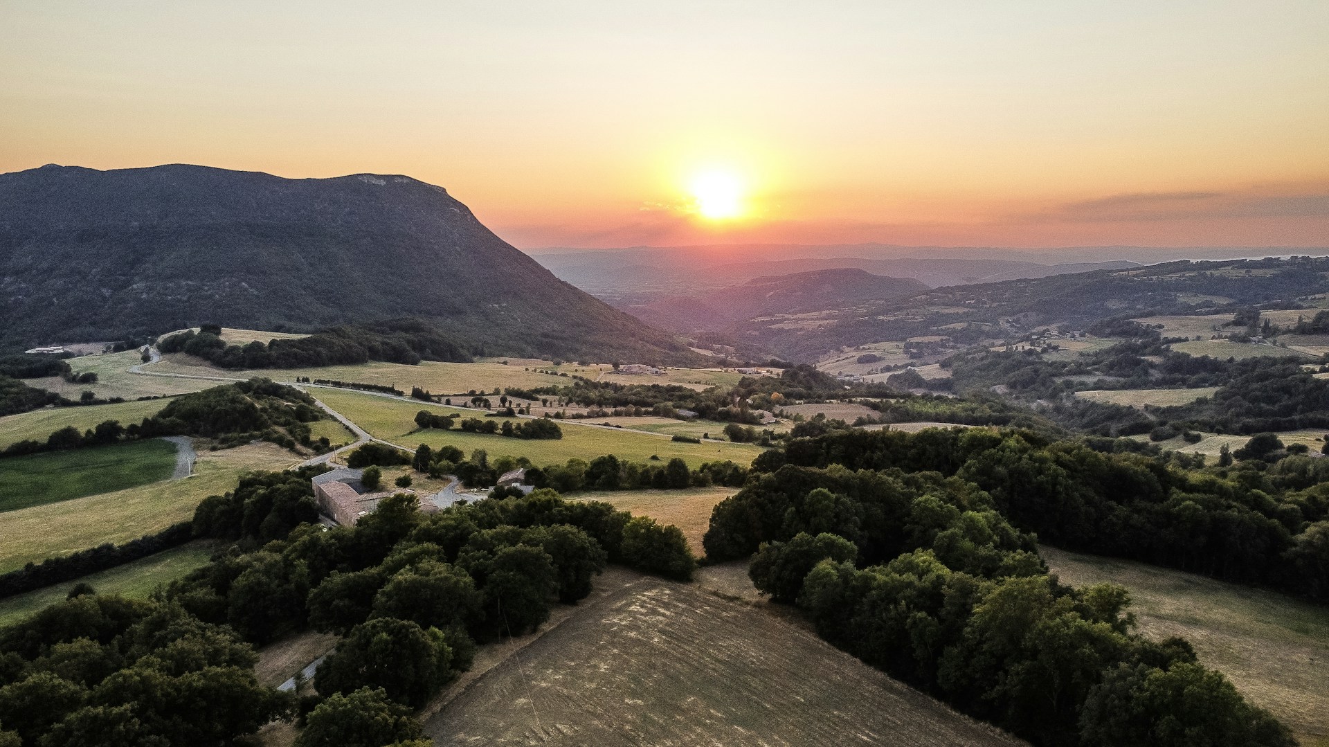 A scenic landscape photograph showcasing a beautiful sunset over rolling hills.