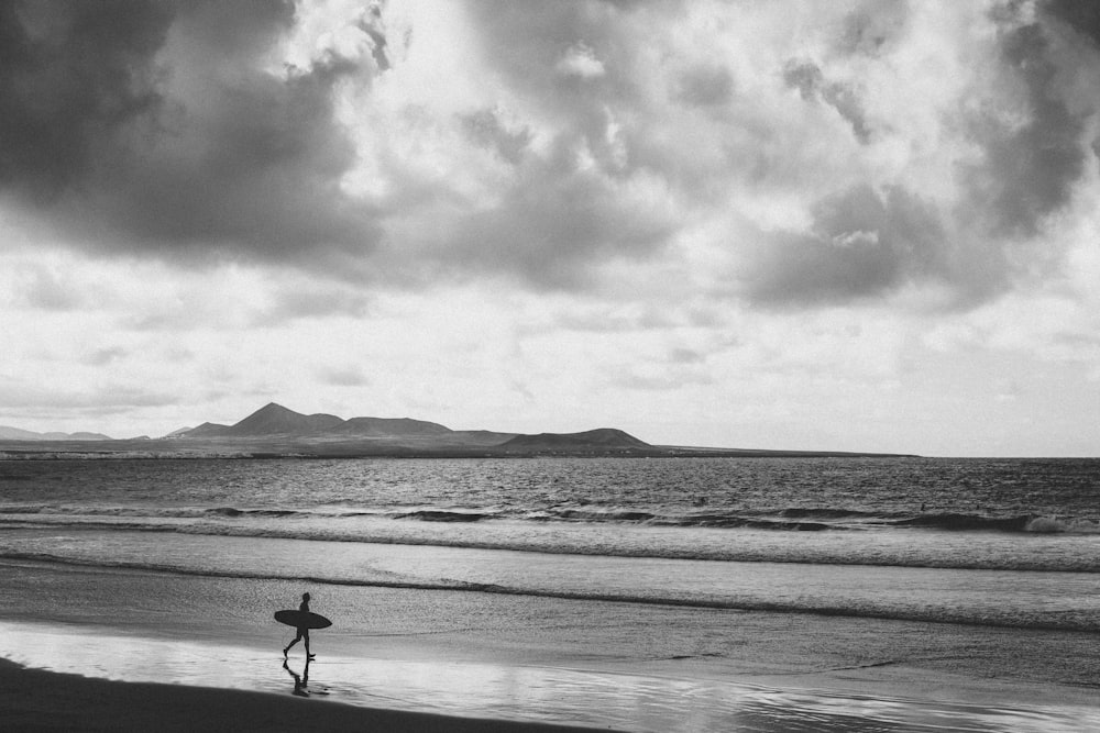 a person carrying a surfboard on a beach