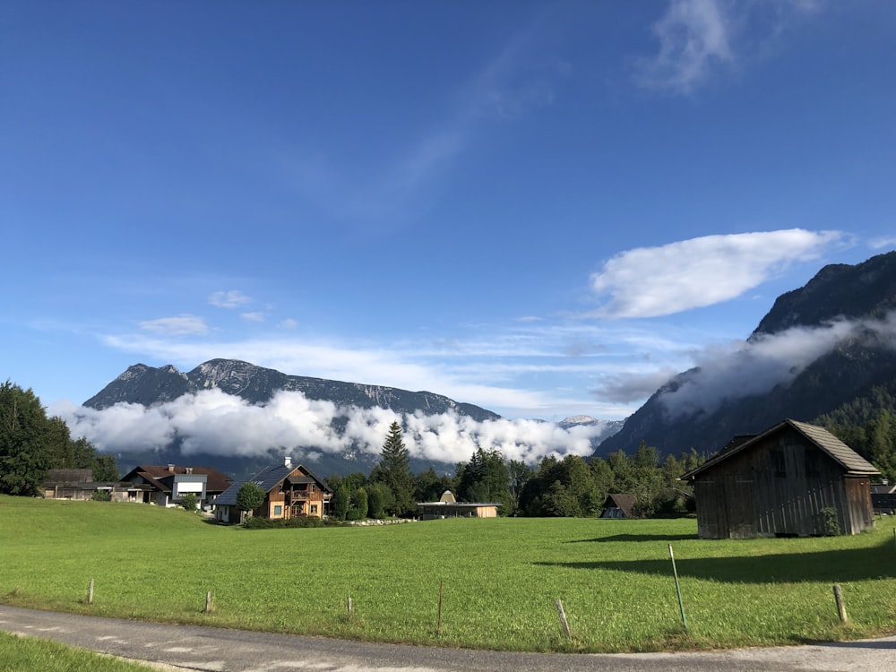 a grassy field with buildings and mountains in the background