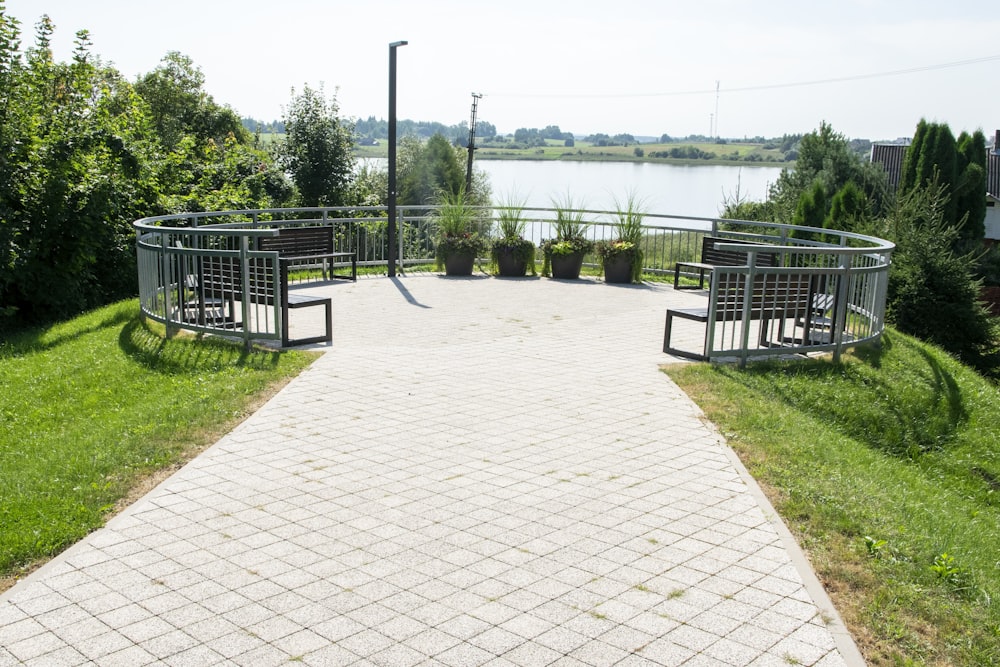 a walkway with benches and a body of water in the background