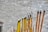 A collection of incense sticks in varying sizes and colors, with some featuring decorative patterns and characters. The sticks are arranged in a holder on a concrete surface, and a few of them are partially burned, emitting faint smoke.