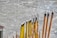 A collection of incense sticks in varying sizes and colors, with some featuring decorative patterns and characters. The sticks are arranged in a holder on a concrete surface, and a few of them are partially burned, emitting faint smoke.