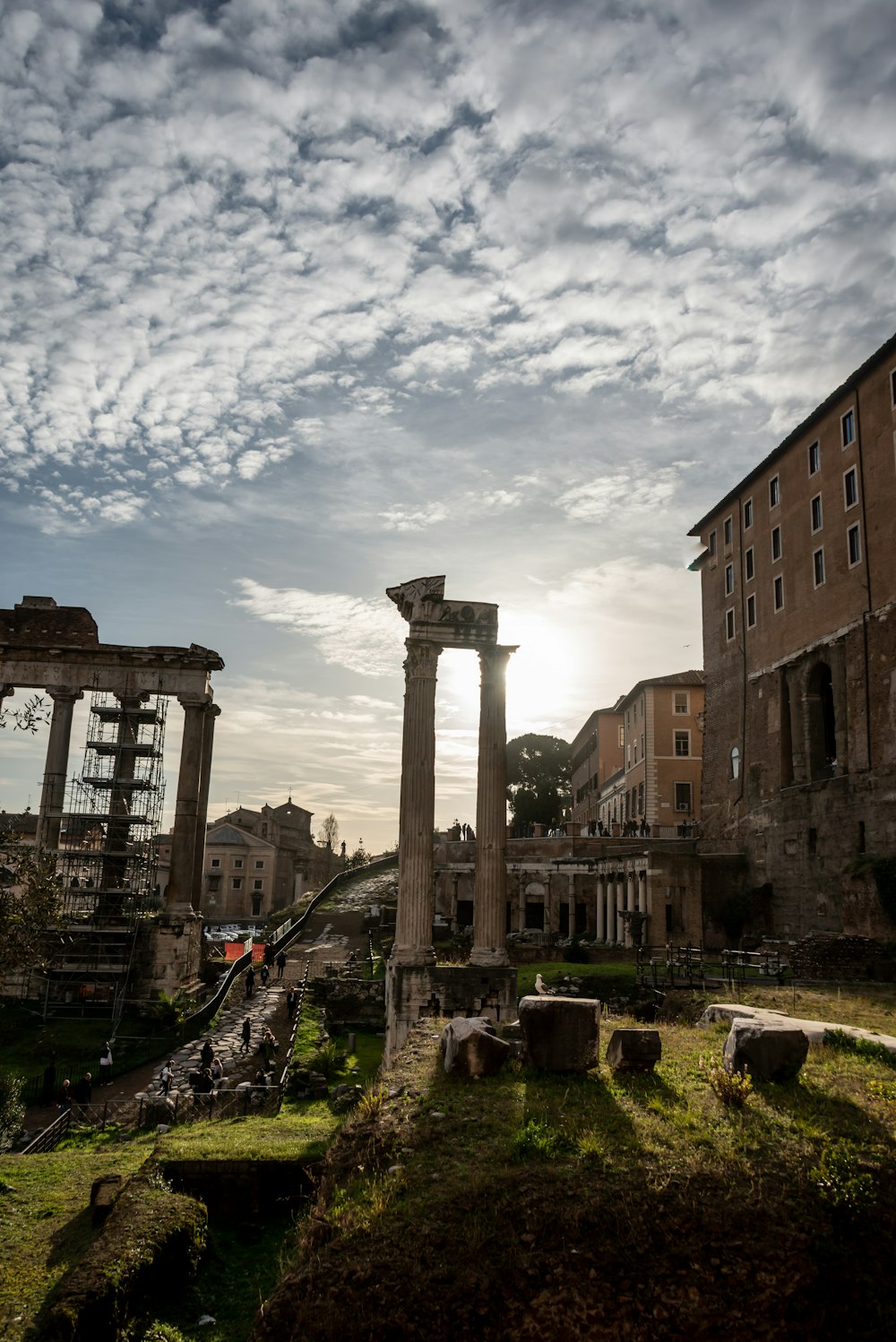 a stone structure with pillars and a building in the background