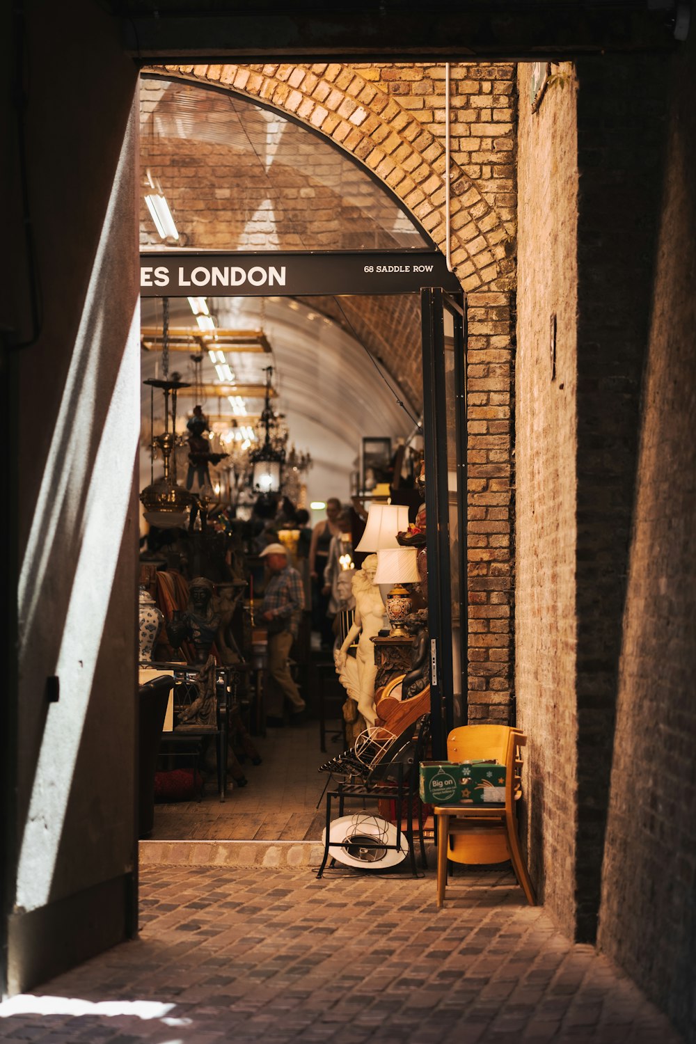 a brick walkway with people and a chair and a sign above it