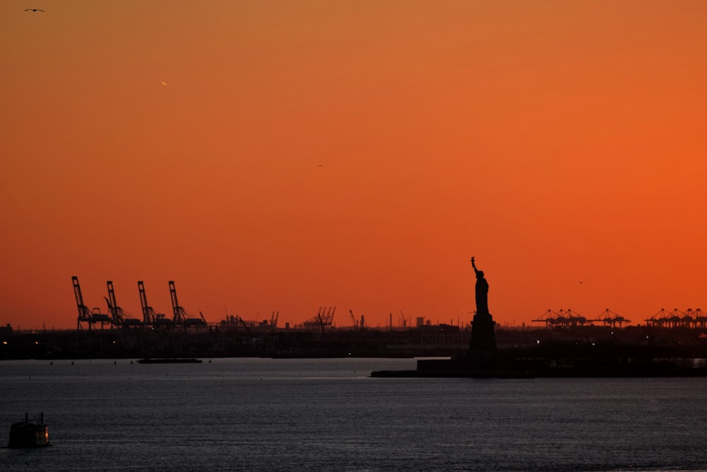 a statue in front of a sunset