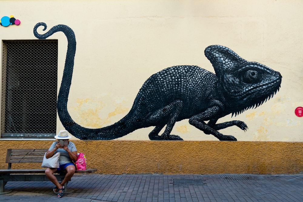 a man and a woman sitting on a bench looking at a large dinosaur