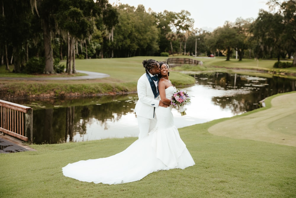 a man and woman kissing in front of a pond