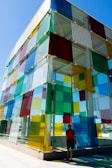 a person standing next to a building with colorful glass panels