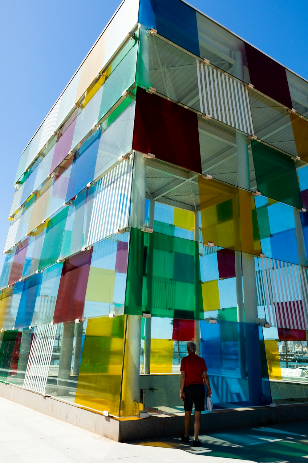 uma pessoa em pé ao lado de um edifício com painéis de vidro coloridos