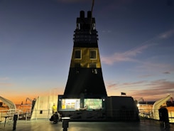 Security personnel patrolling a large cargo ship deck at sunset