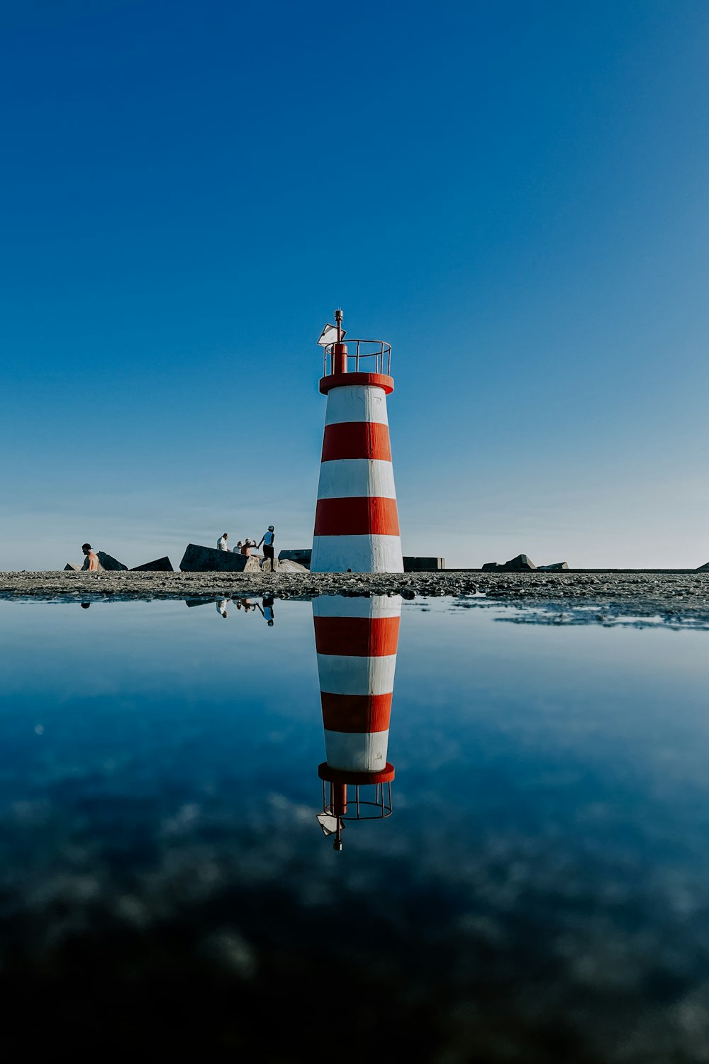 a red and white lighthouse sitting on top of a body of water