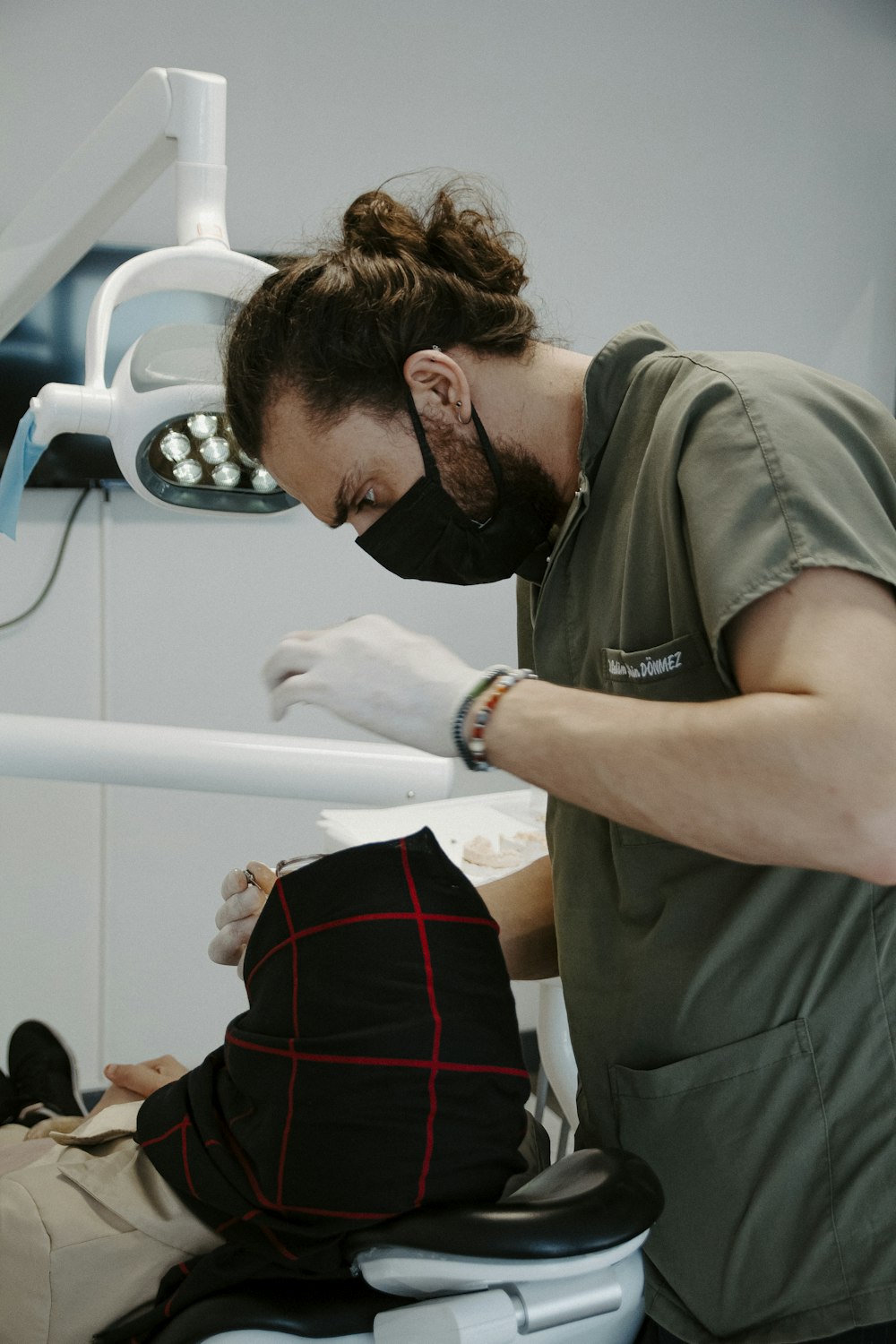 um homem em uma máscara olhando para uma pessoa em uma maca